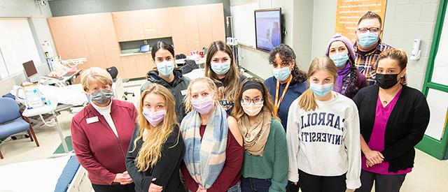 a group of students wearing face masks in a nursing class room.